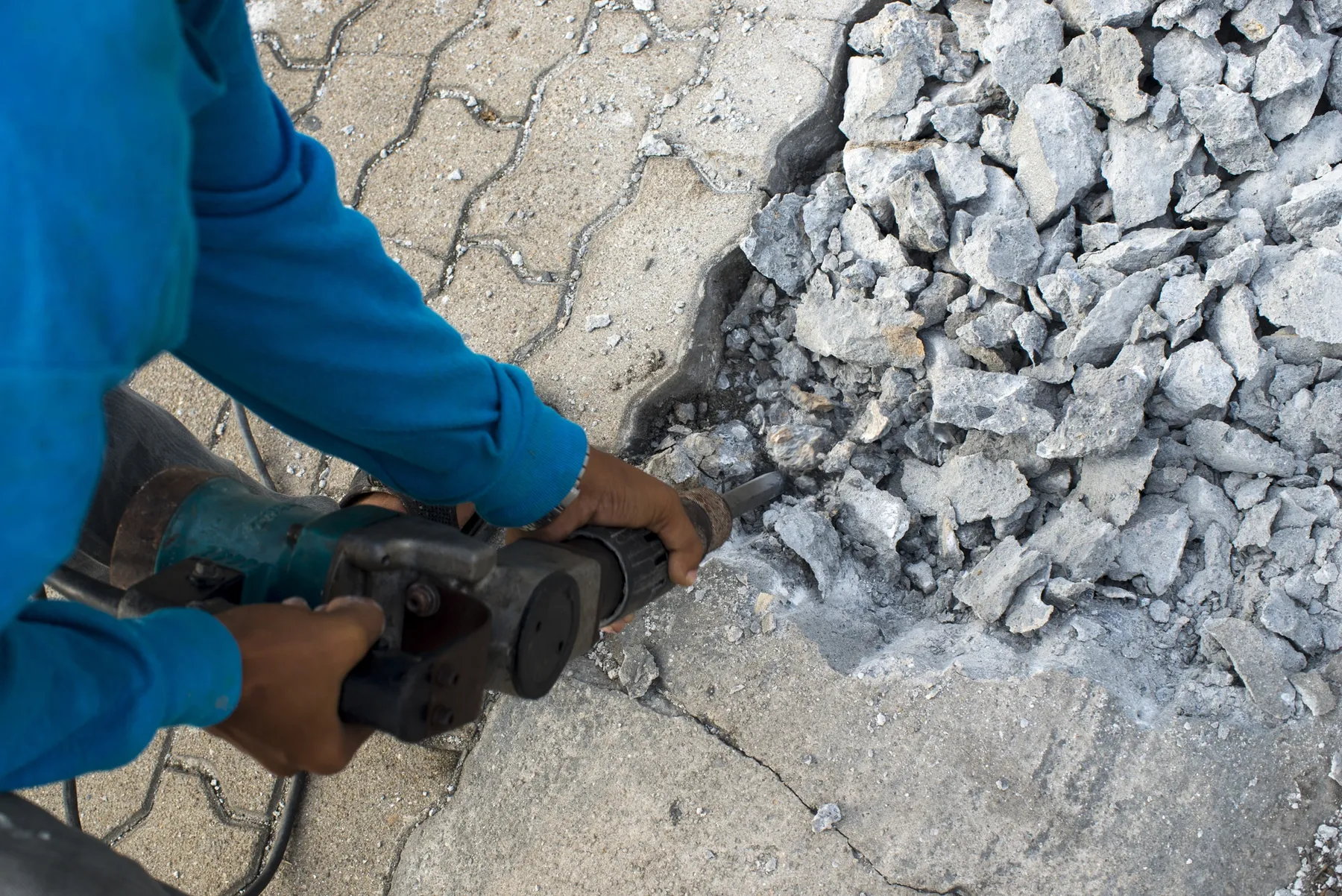 Worker breaking up a concrete slab with a jackhammer