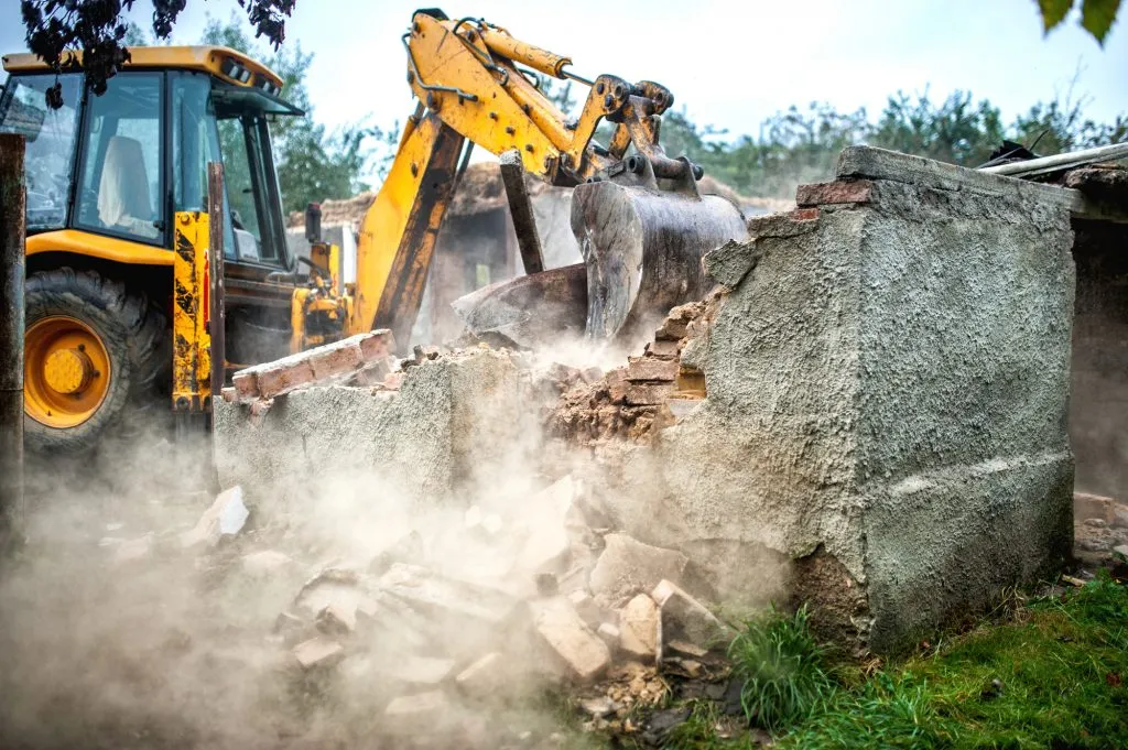 Backhoe knocking down a brick structure during house clearing