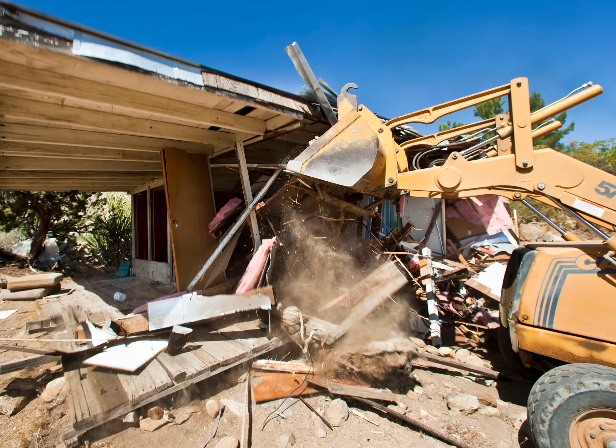 Machine tearing down the timber frame of a house