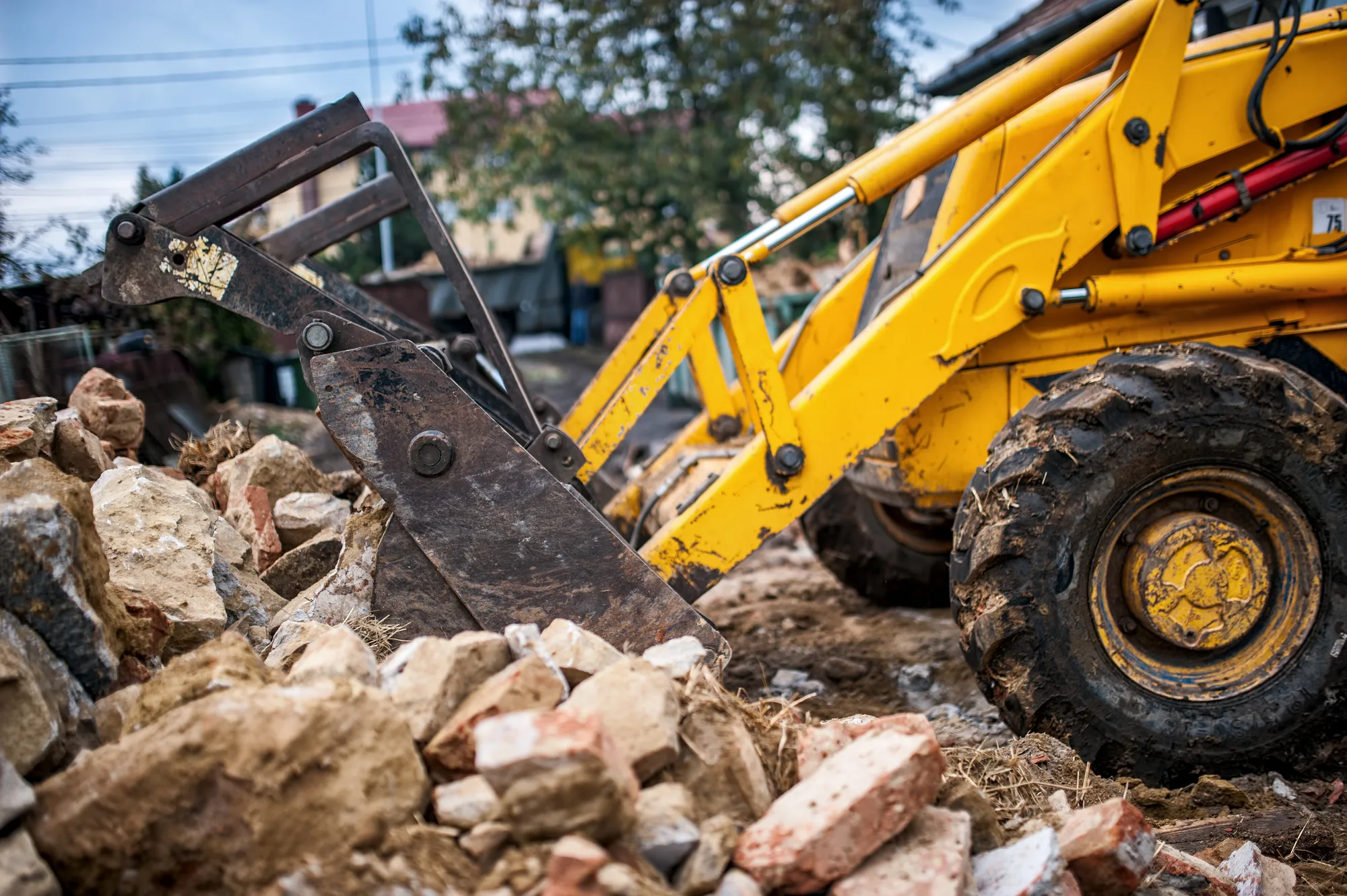 Backhoe clearing brick rubble after a house demolition