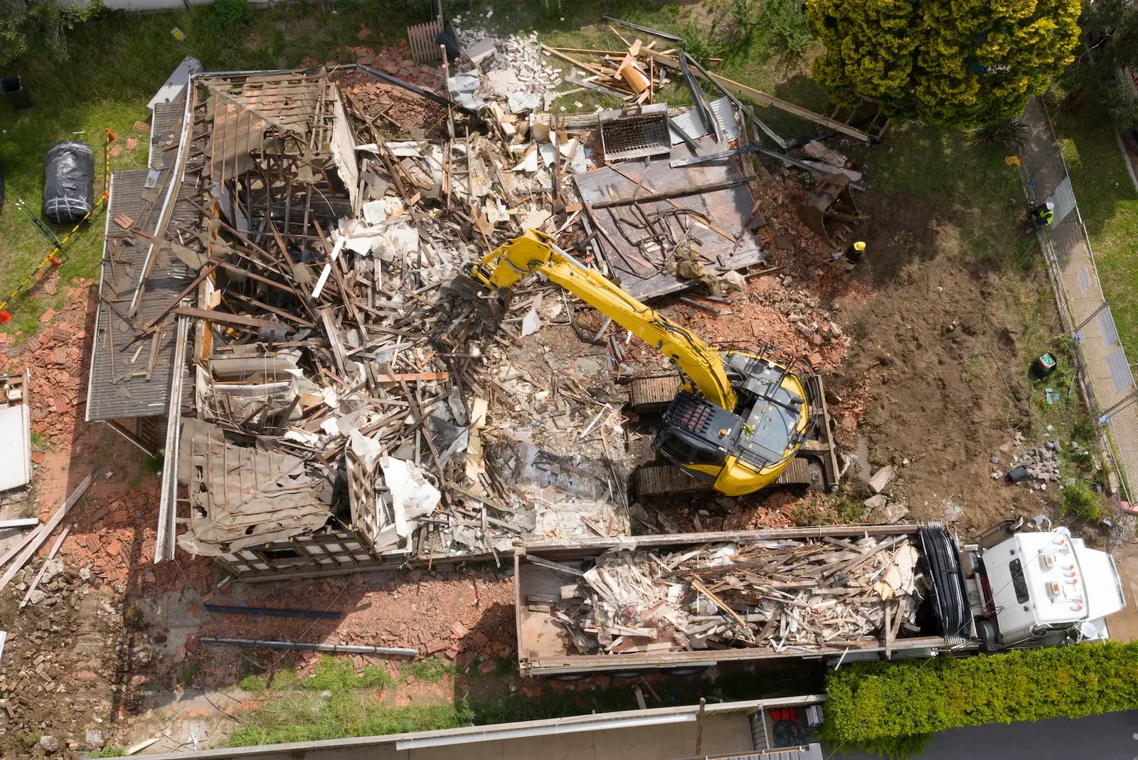 Aerial view of a house demolition with excavator and truck