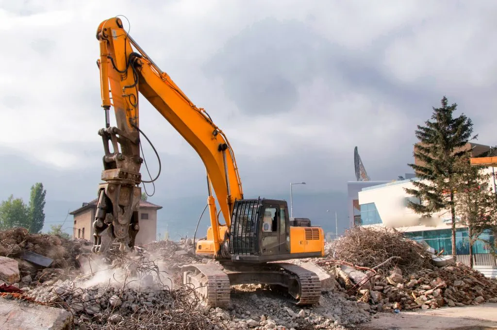 Excavator with a demolition attachment on a cleared site