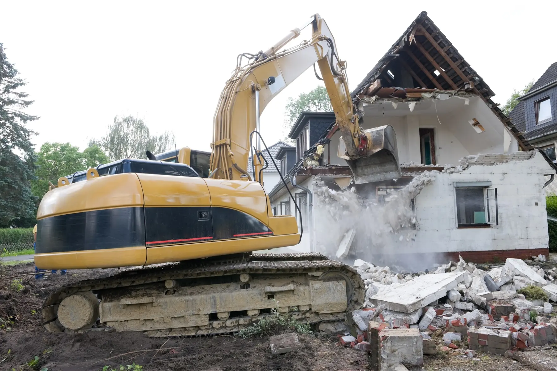 Excavator demolishing a two-storey brick house